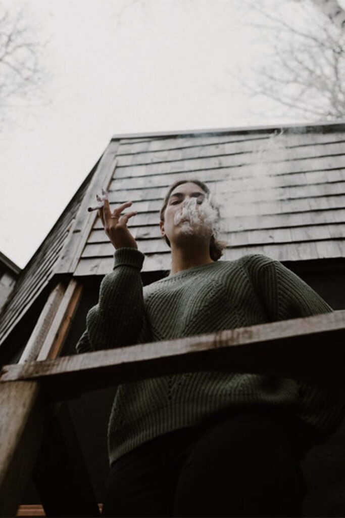 Depiction of a person outdoors breathing out a puff of smoke.