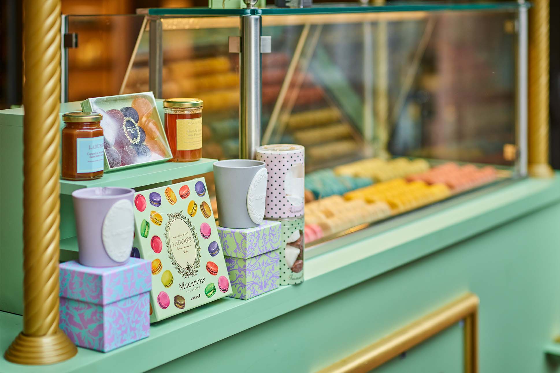 Close-up photo of a food cart in a pastel green with gold accents. The cart hold Lauderee macarons and boxes.