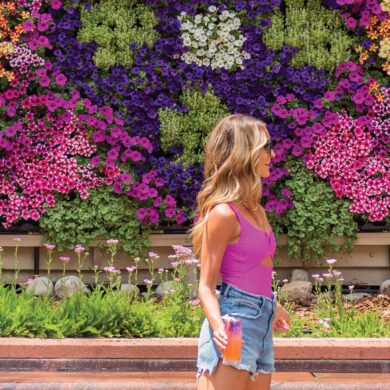 a person standing in front of a wall of flowers