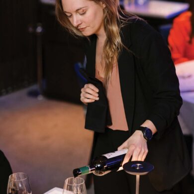 a person pouring wine into glasses