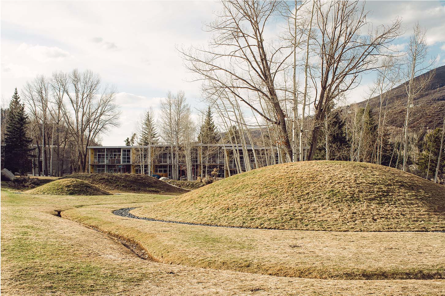 a building with a grassy hill and trees