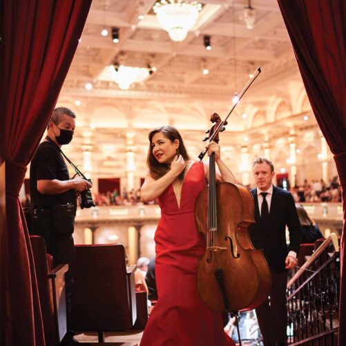 a person in a red dress holding a cello and a person in a mask