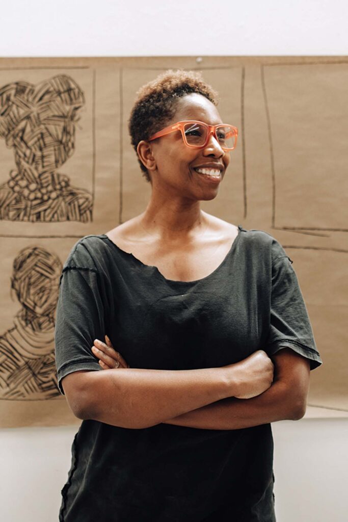 a person with arms crossed in front of a cardboard drawing