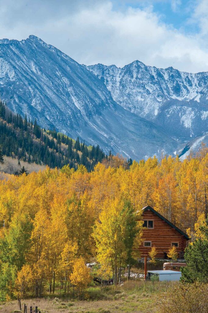 a cabin in the woods with mountains in the background