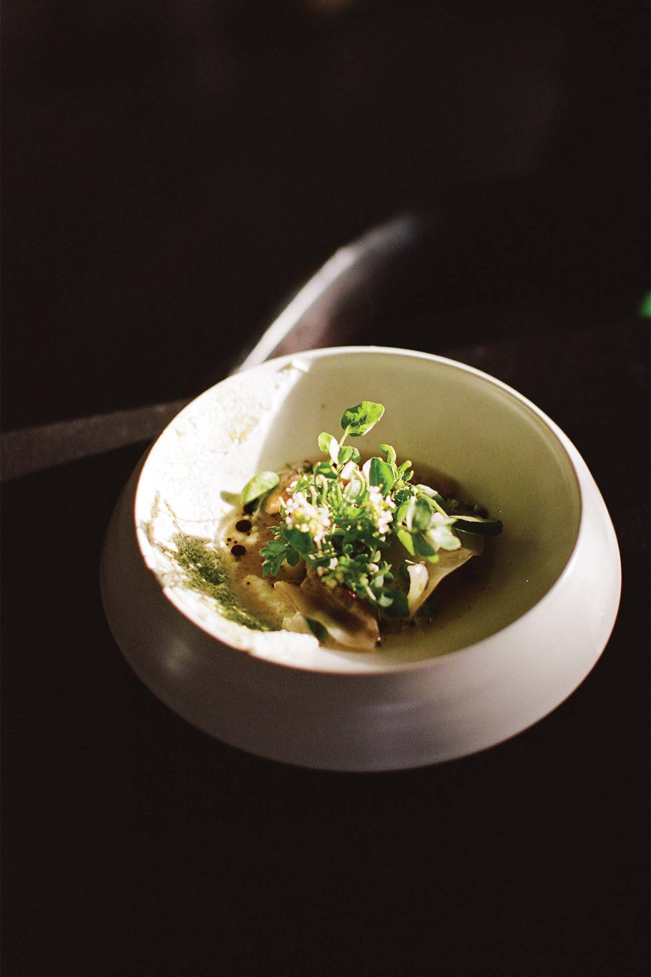 A bowl of food topped with microgreens.